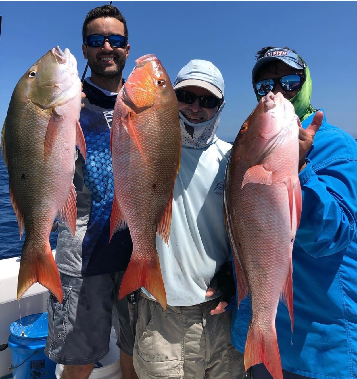Anglers holding large mutton snapper caught offshore on the Mako 30ft fishing charter Miami
