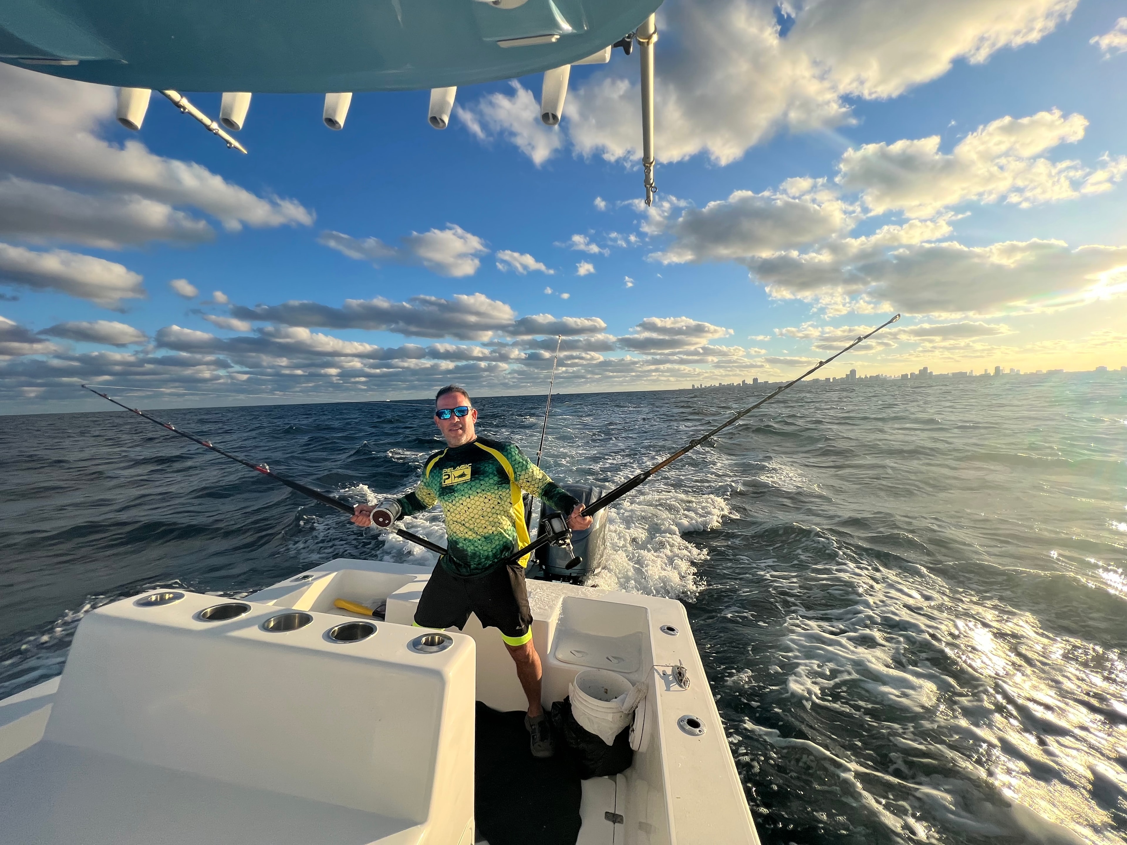 Captain trolling with multiple rods off the stern of the Mako 30ft with Miami skyline in background